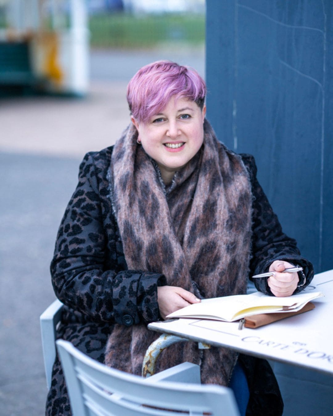 Close up image of a white woman with brown hair on a sofa writing in a journal. The image does not show her face, and focusses on the fact that 'healing is happening' as she journals